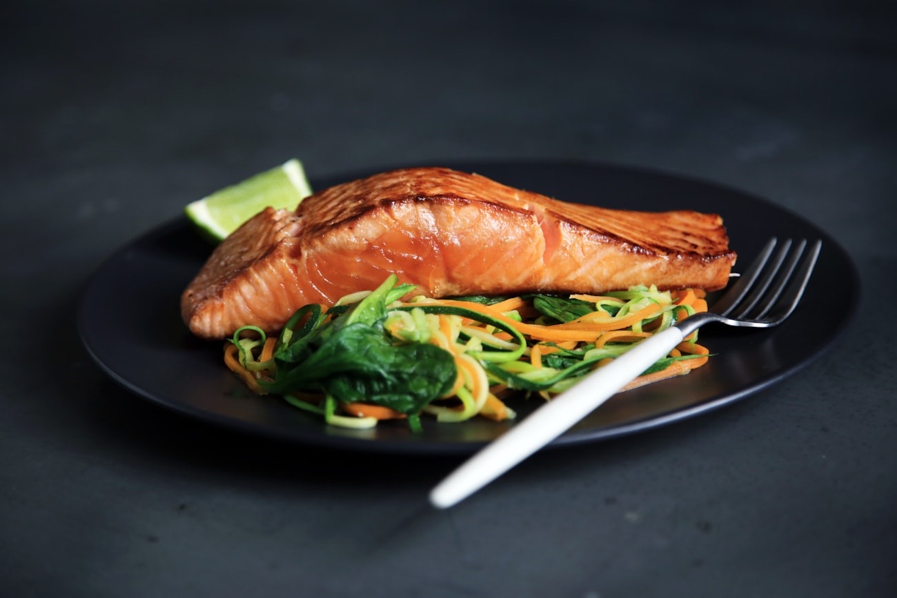 Grilled salmon fillet with spiralised vegetables on a dark plate
